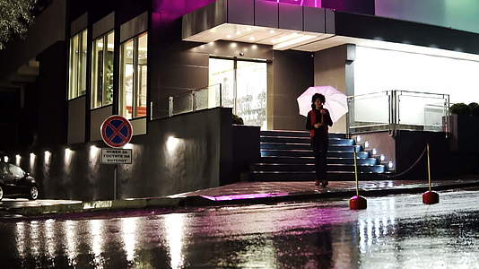 黑发美女在雨夜带着雨伞行走视频的预览图