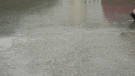 女孩和男孩的腿在路边灰色潮湿的雨中行走视频的预览图