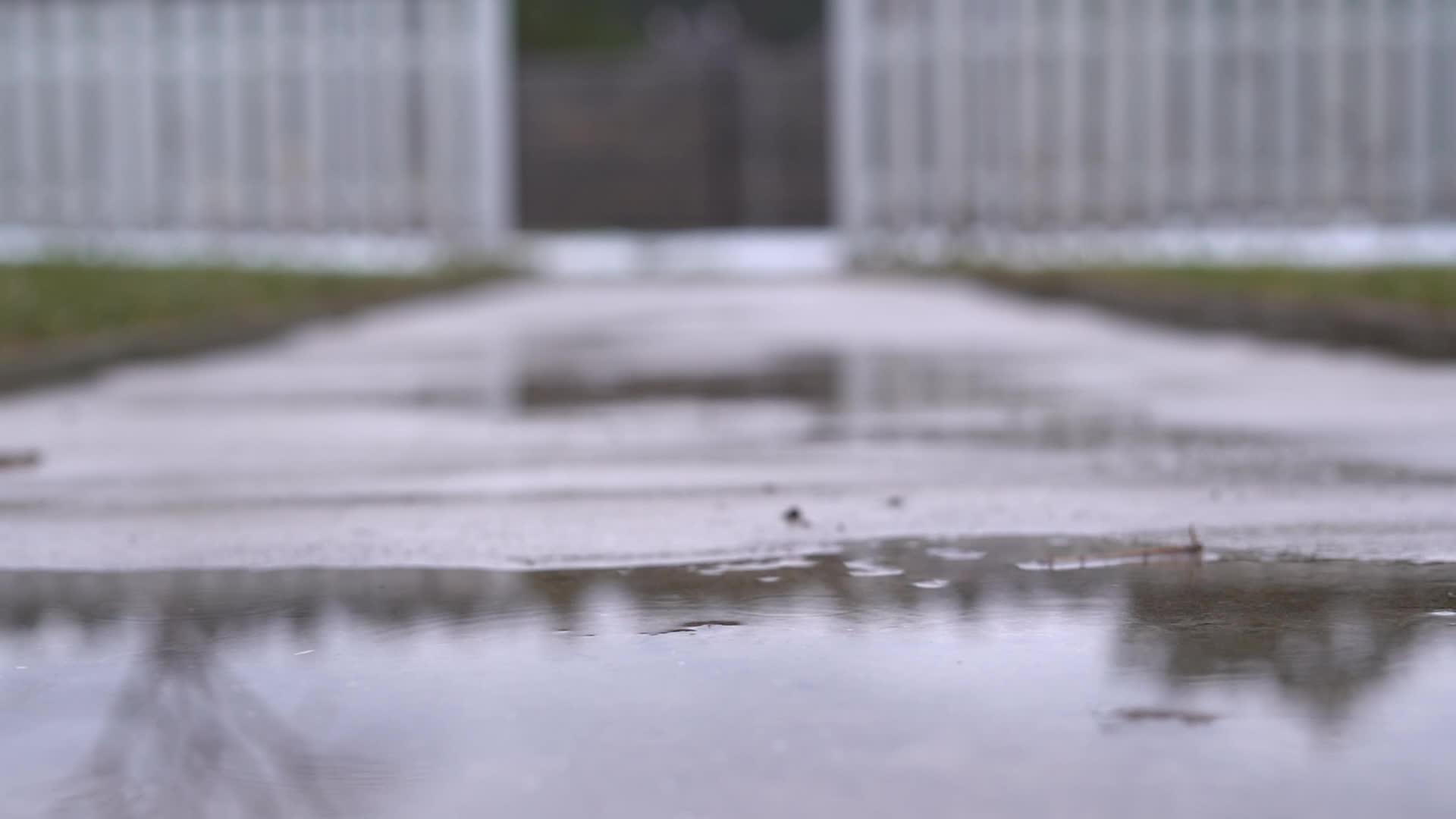 雨滴落在黄昏的街道上在一条小路的水坑里视频的预览图
