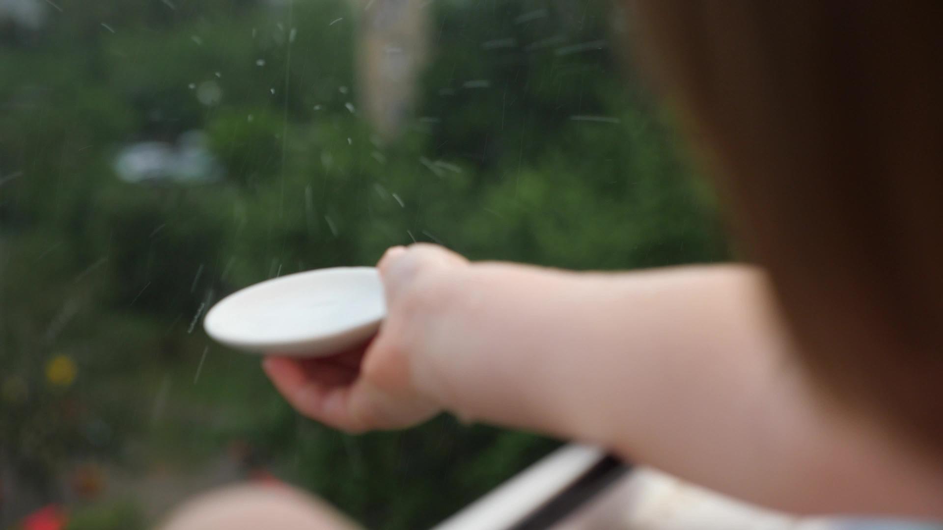 小手在模糊的背景下捕捉雨滴纯生态小女孩玩雨滴视频的预览图