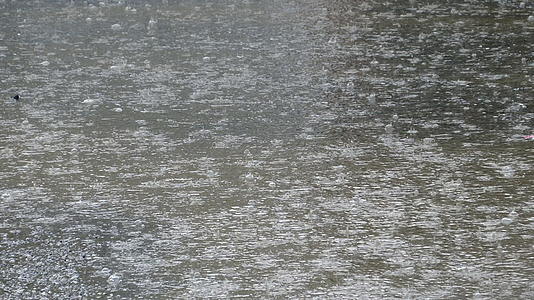 在被洪水淹没的街道水坑的背景下雨滴滴落在小便上视频的预览图