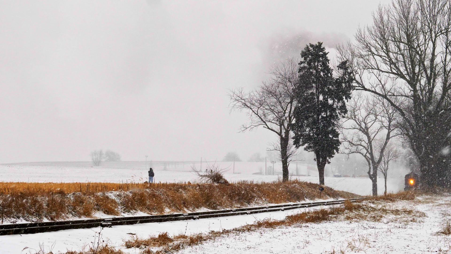 当蒸汽机在暴风雨中接近时这名男子在铁路公路上行走视频的预览图
