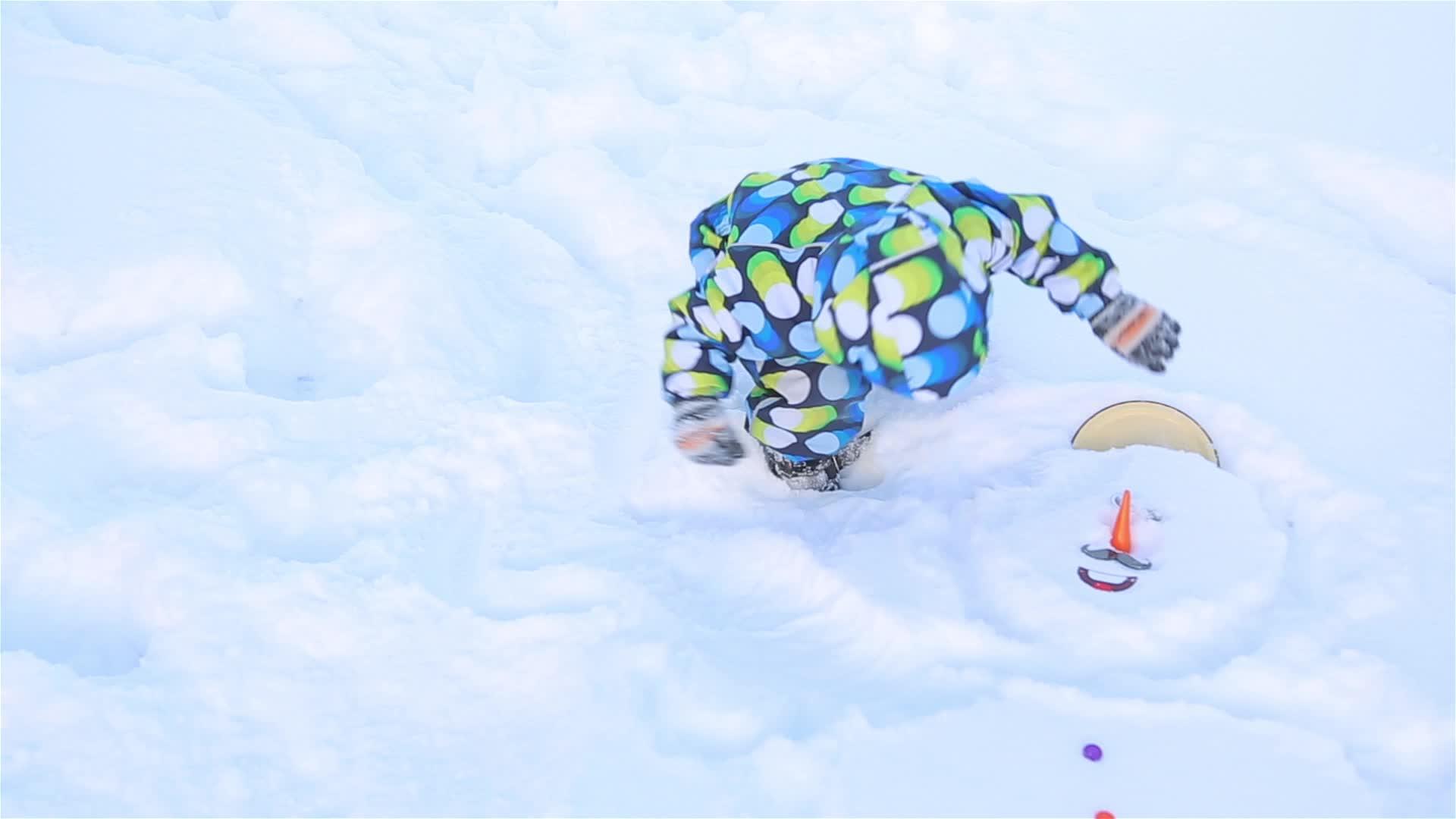 一个小男孩试图从雪人身上拔出一个光滑的鼻子视频的预览图