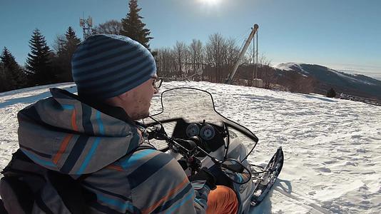 穿着夹克骑着雪车下到阳光明媚的森林视频的预览图