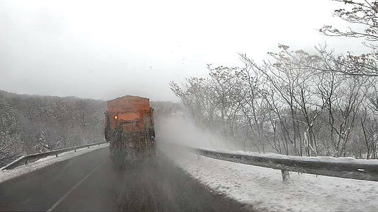 雪花服务卡车和灰渣在路上撒盐防止冬季暴风雪缓慢移动视频的预览图