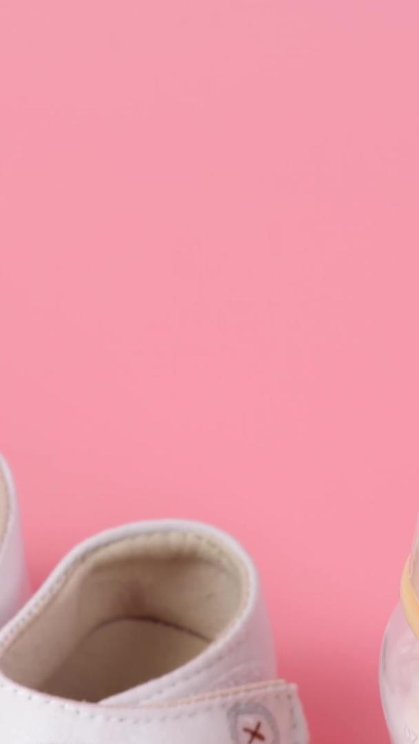粉红色背景的婴儿鞋和可爱的小瓶子组合视频的预览图