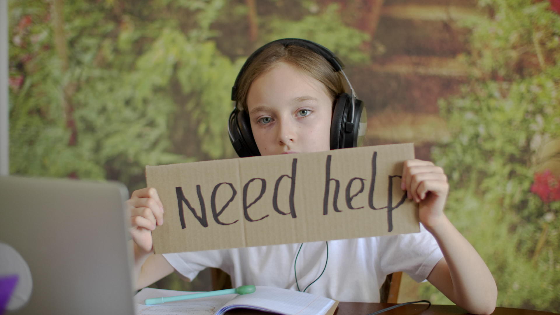 一个戴着耳机的悲伤女孩拿着一台带有铭文的纸板平板电脑需要帮助视频的预览图