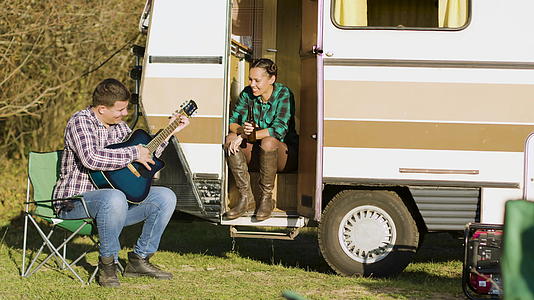 男朋友面前的复式露营车在吉他上唱歌视频的预览图
