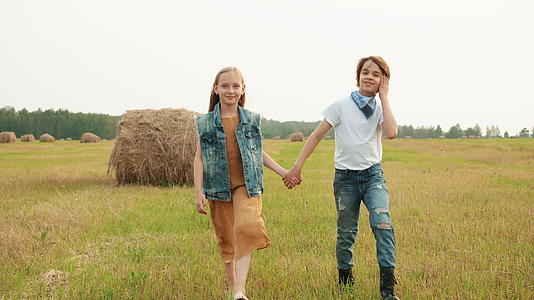 走在干草堆背景下的农村田野里的年轻夫妇是快乐的年轻人视频的预览图