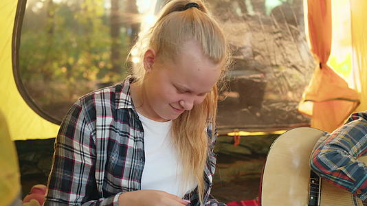 十几岁的女孩在露营帐篷里用吉他音乐写歌男孩正在旅行视频的预览图