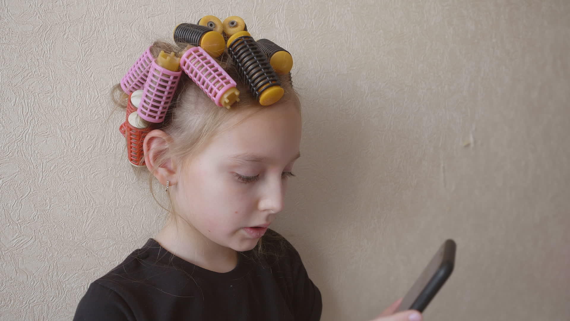 在轻墙背景中使用智能手机卷发的女孩视频的预览图