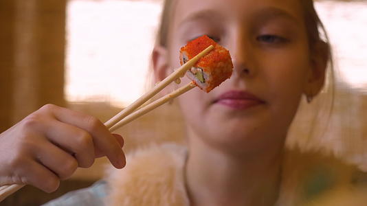 一个十几岁的女孩正在亚西餐馆吃日本寿司卷和筷子视频的预览图