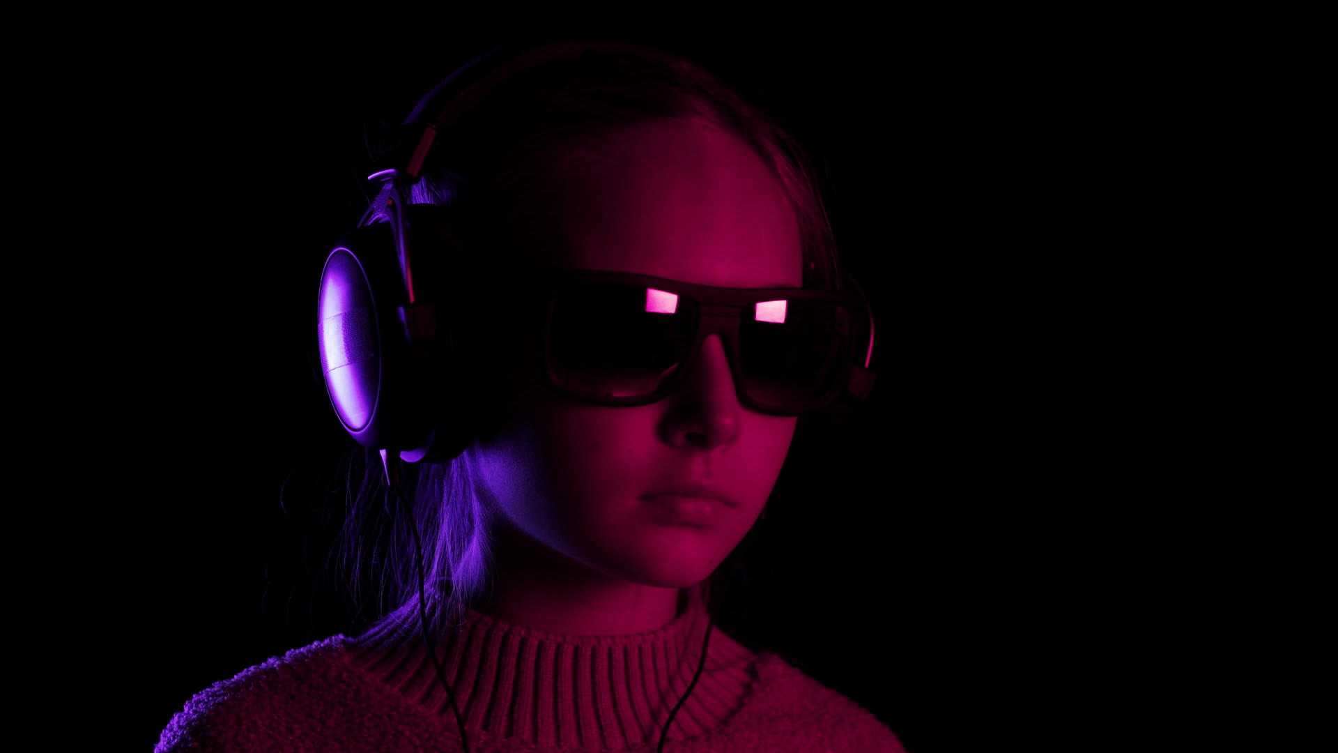 十几岁的女孩在黑暗的工作室里戴着耳机红色和蓝色的灯光视频的预览图