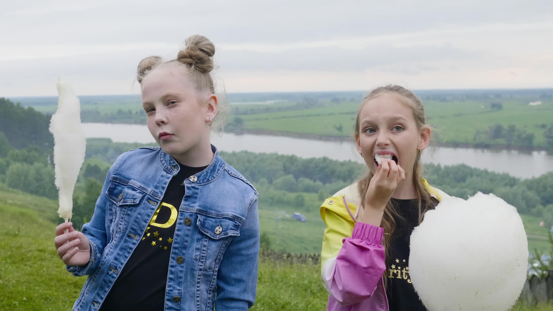 两个十几岁的女孩在夏天的森林和河流景观中吃甜棉花视频的预览图