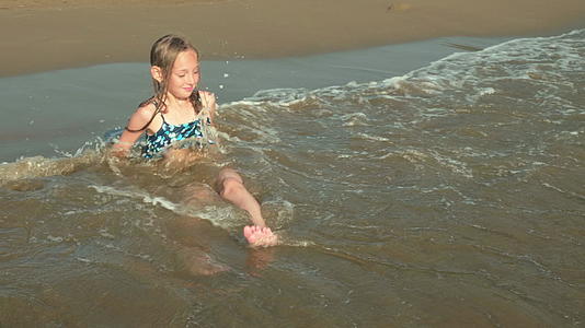 十几岁的女孩坐在海边享受海浪在海滩上玩耍享受快乐的旅游视频的预览图