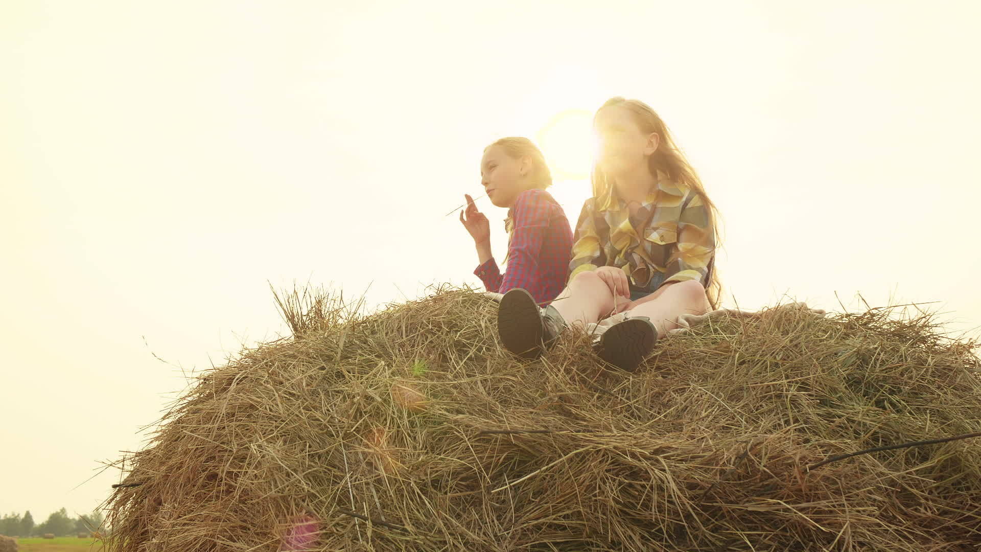 两个十几岁的女孩坐在干草堆里晚上日落视频的预览图