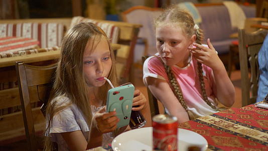 十几岁的女孩在餐桌上看智能手机用手机看视频视频的预览图