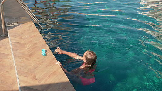 十几岁的女孩在度假村酒店的室外水池里游泳漂浮在蓝色的水池里视频的预览图
