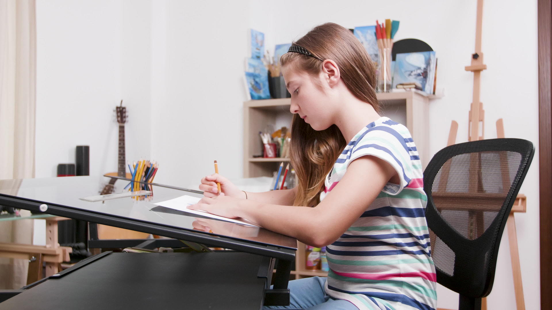 女孩坐在书桌旁用铅笔画东西视频的预览图