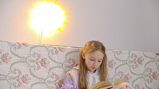 穿着睡衣的女孩用夜灯看书在卧室里放松视频的预览图