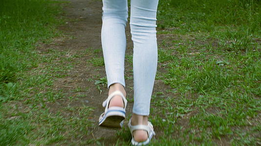 十几岁的女孩穿着蓝色紧身裤和凉鞋然后在草地上跑步视频的预览图