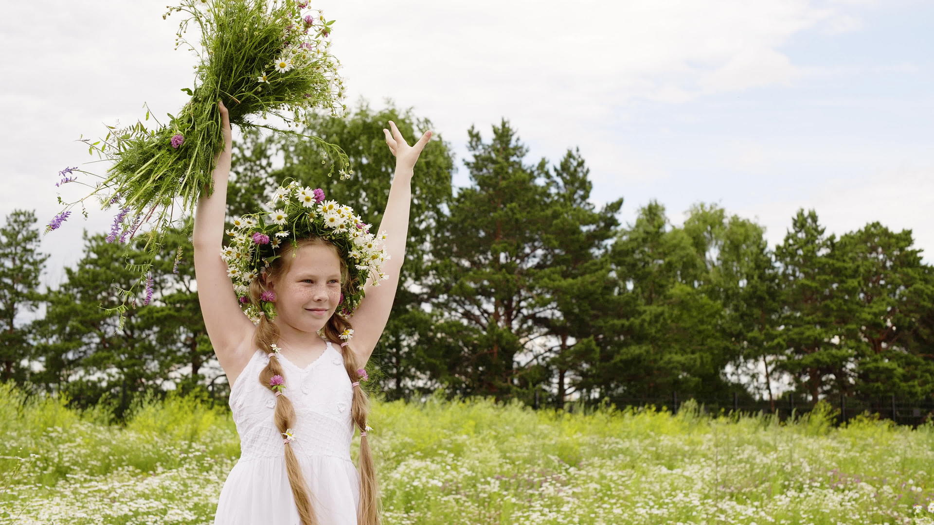 花环里的女孩举起双手把草甸花放在绿色的田野视频的预览图