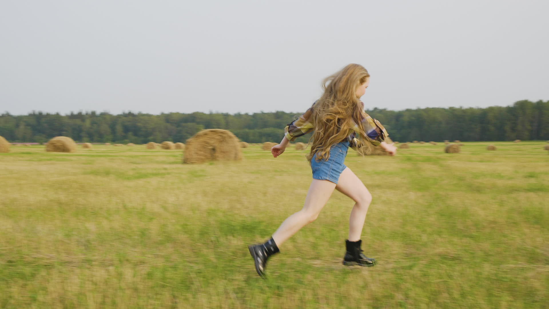 穿着短牛仔裤的快乐女孩和在农村田野里跑步的格斗衬衫校对视频的预览图