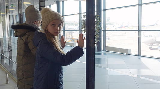 青少年女孩正在等待机场候机楼的全景窗口视频的预览图