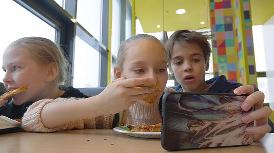 青年朋友在便士吃快餐时在手机上看电影视频的预览图