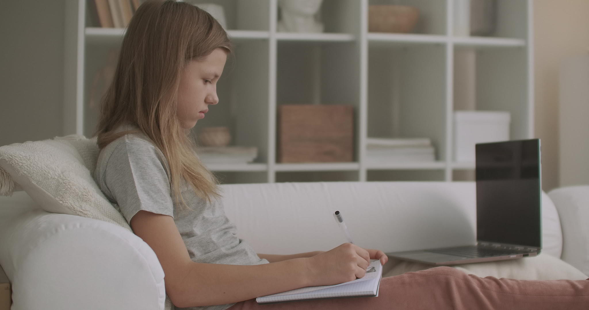 放学后青少年女孩在公寓房间里做作业写练习本坐在沙发上视频的预览图
