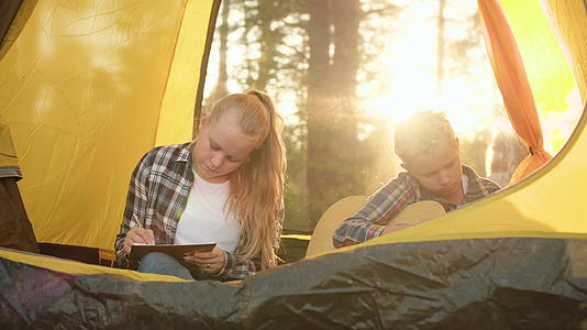 年轻的男孩和女孩在夏天的远足、露营、帐篷和笔记本上画画视频的预览图