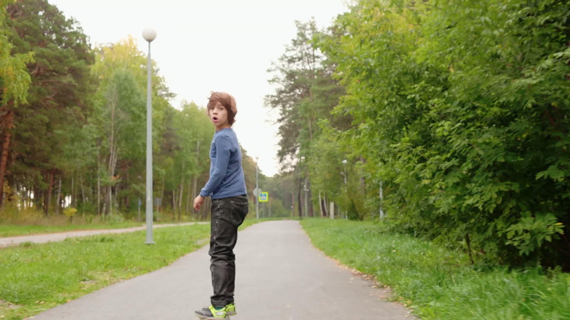 男孩在夏季城市公园赛道上拍摄的滑板上玩滑板然后看着男孩视频的预览图