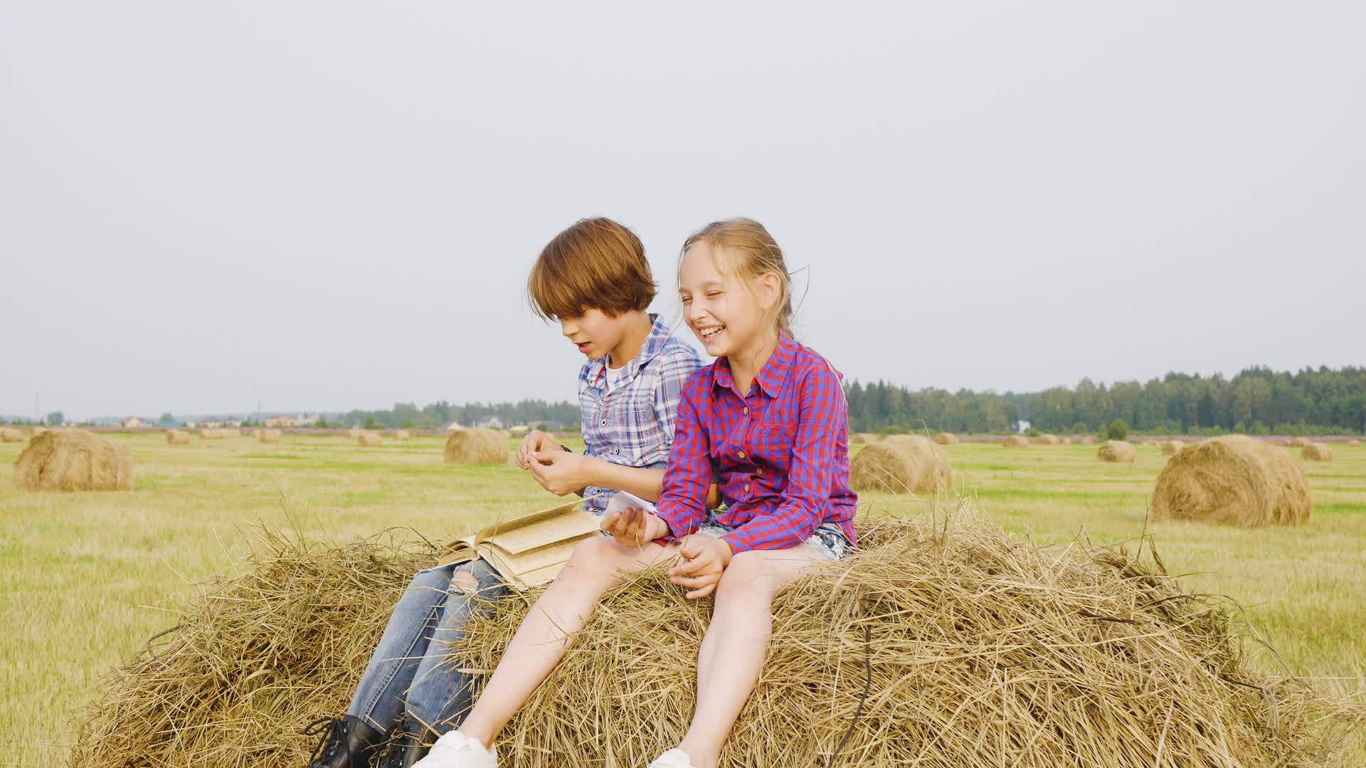 十几岁的男孩和女孩坐在农村的干草堆上视频的预览图