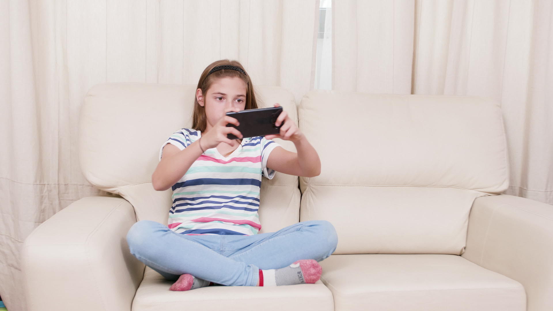 睡在沙发上的女孩在智能手机上玩游戏视频的预览图