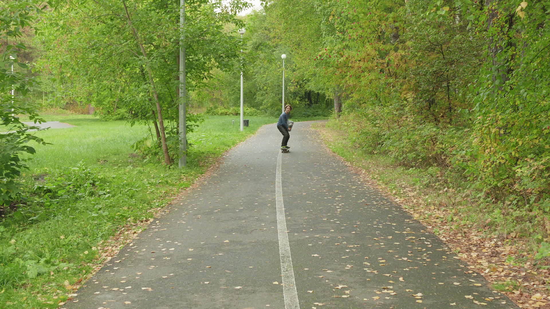 十几岁的男孩在夏季公园的小路上骑着长长的小男孩视频的预览图