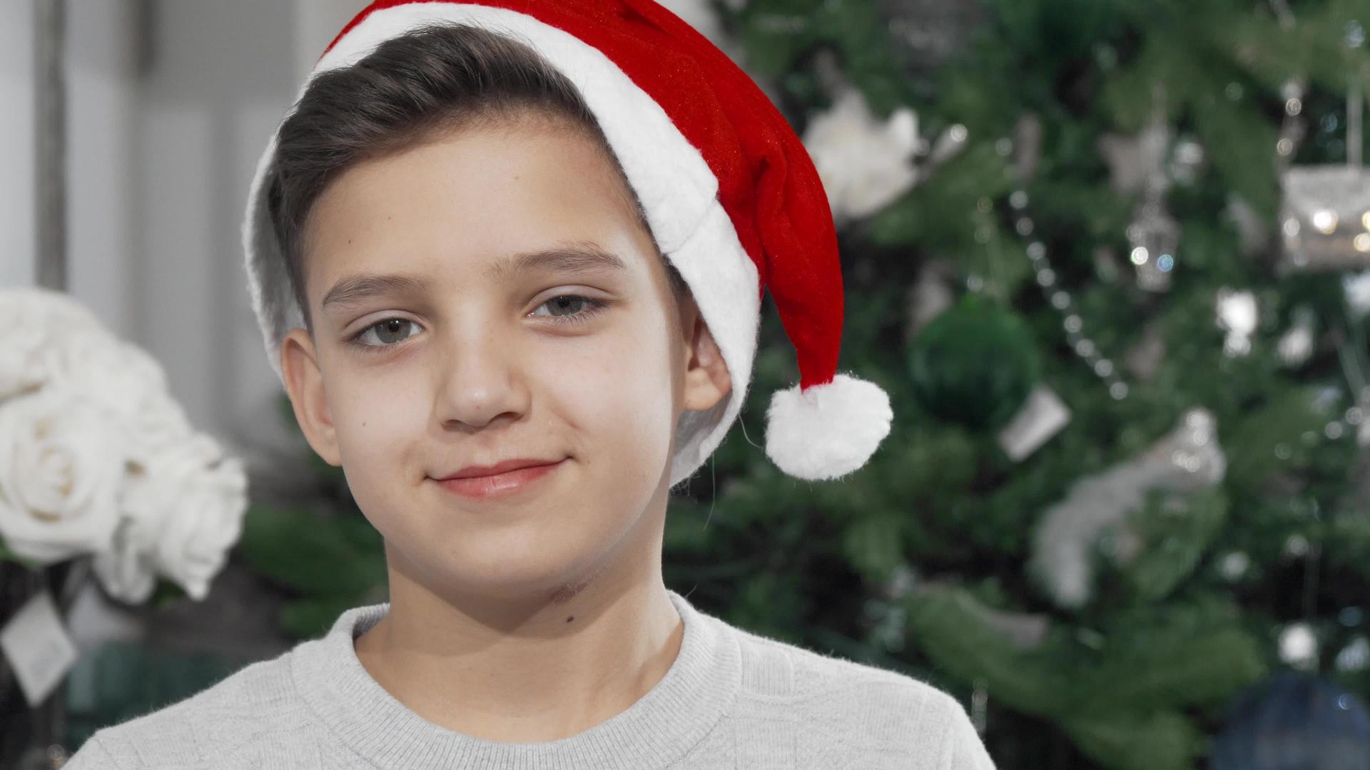 可爱的小男孩戴着圣诞帽子静静地看着镜头视频的预览图