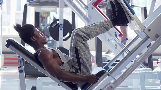 非洲强壮的男人在健身房用脚印机锻炼视频的预览图