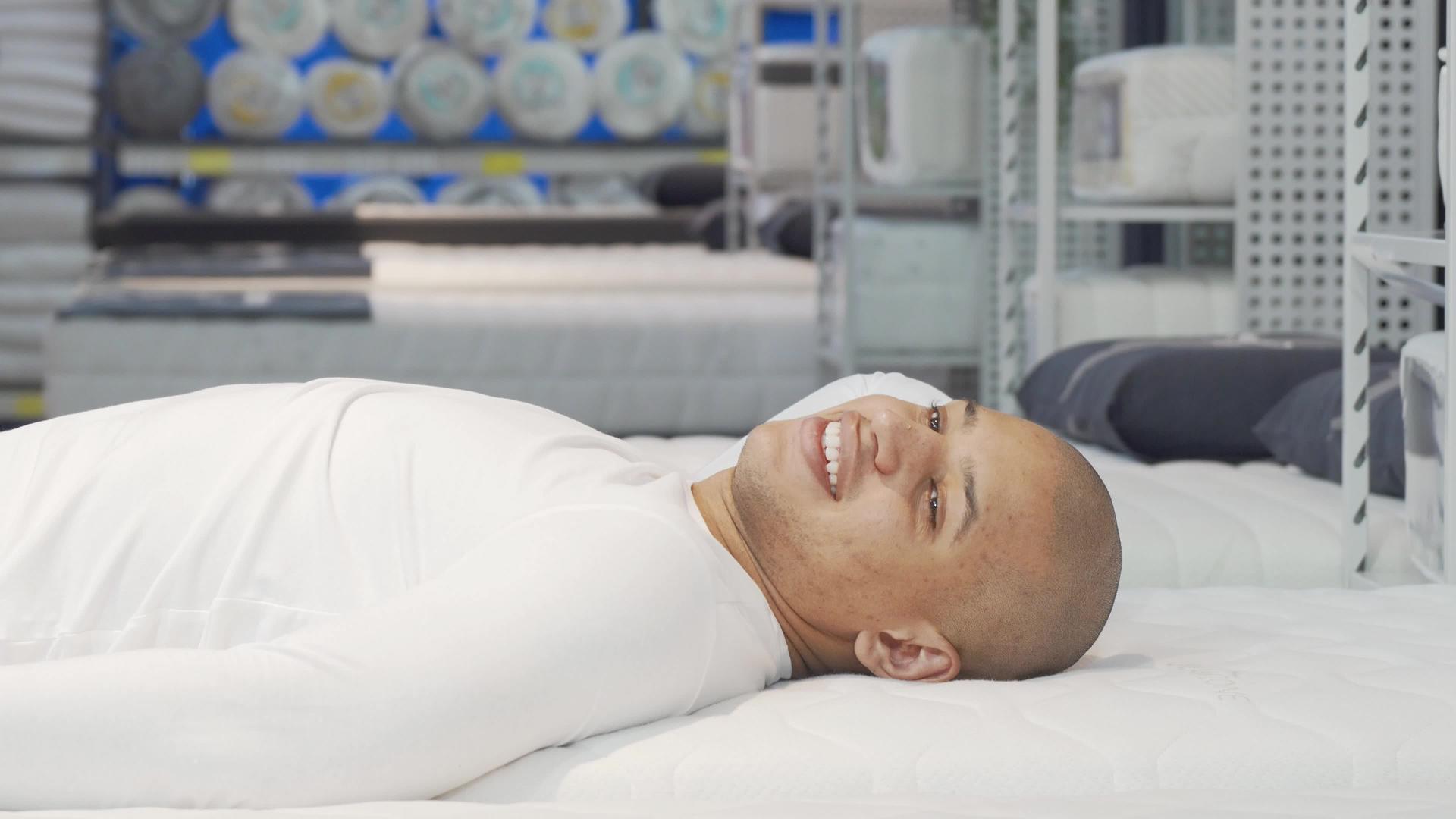 快乐的非洲男人躺在家具店的塑料床垫上视频的预览图