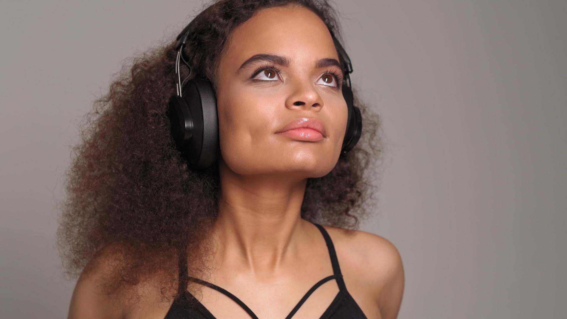 迷人的非裔美国女孩戴着耳机闭上眼睛欣赏音乐视频的预览图