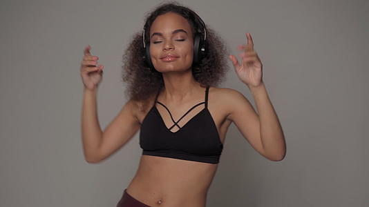 带着音乐跳舞的非裔美国女孩闭着眼睛听音乐戴着音乐视频的预览图