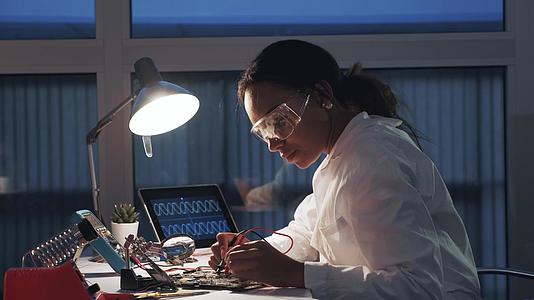 女性电子在实验室与多米测试仪等电子设备一起工作视频的预览图