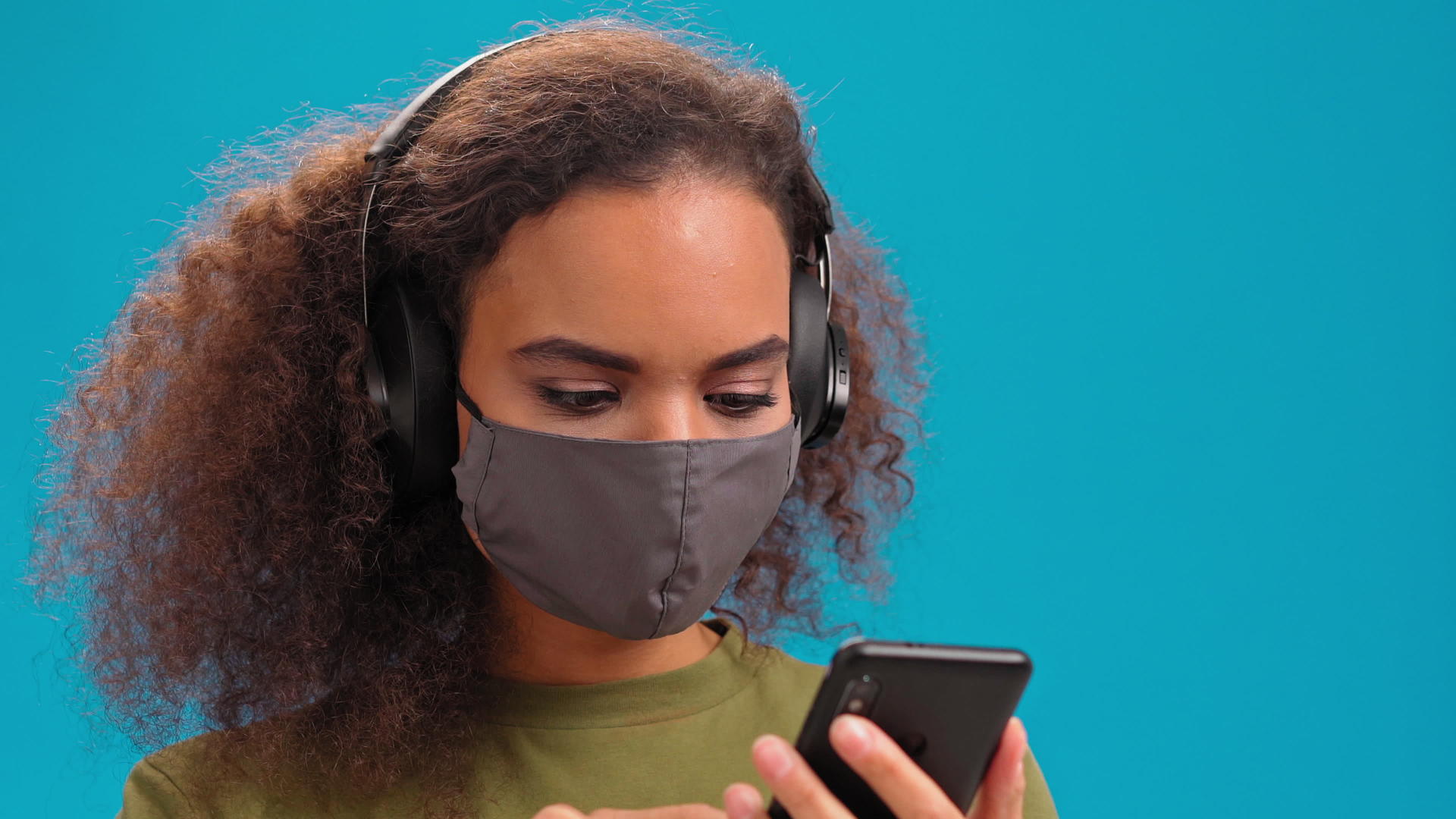 拥有智能手机的非裔美国女孩戴着医用口罩以避免传播视频的预览图