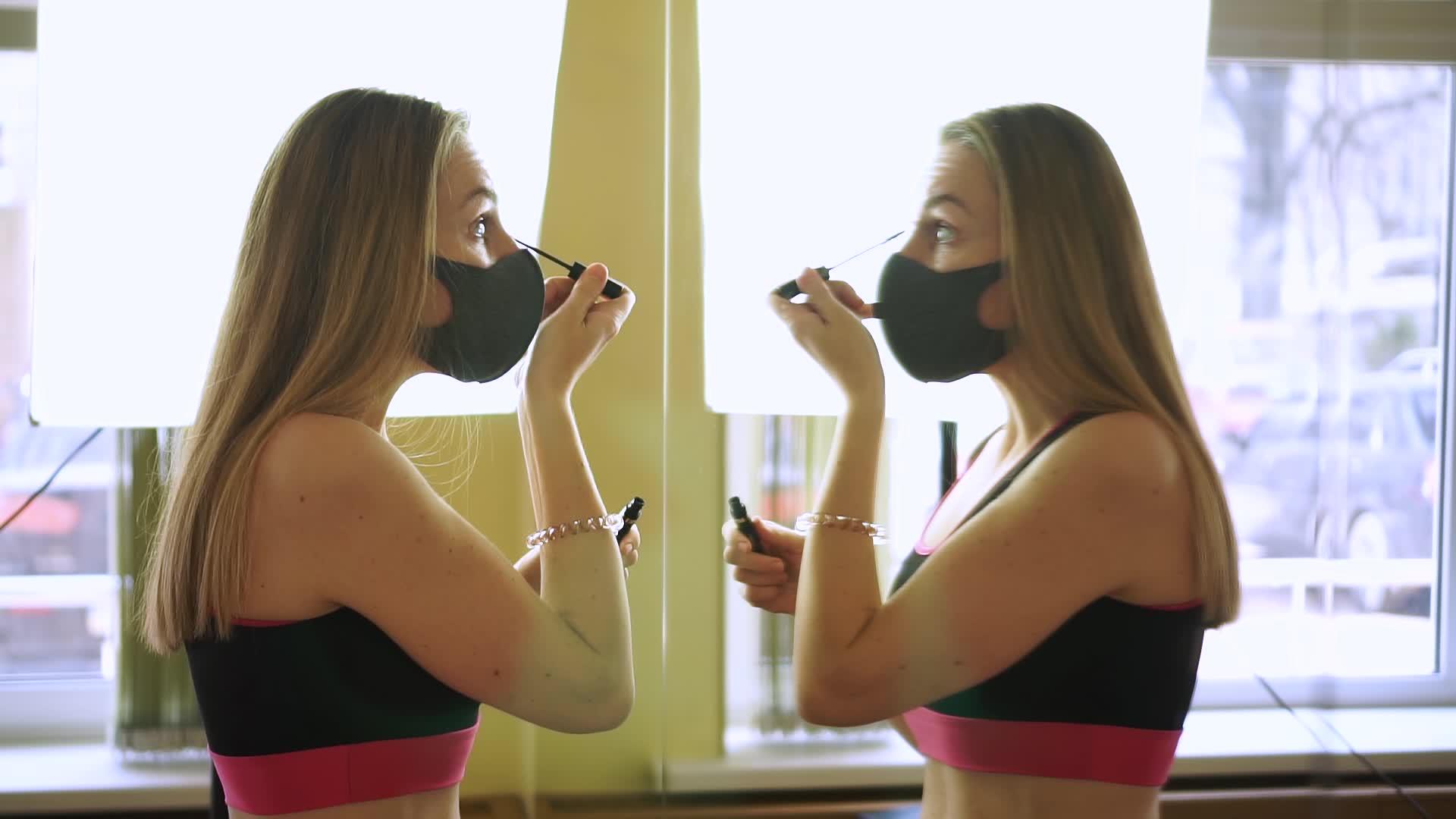年轻的黑人女性戴着黑色保护面具在大镜子前做眼妆视频的预览图