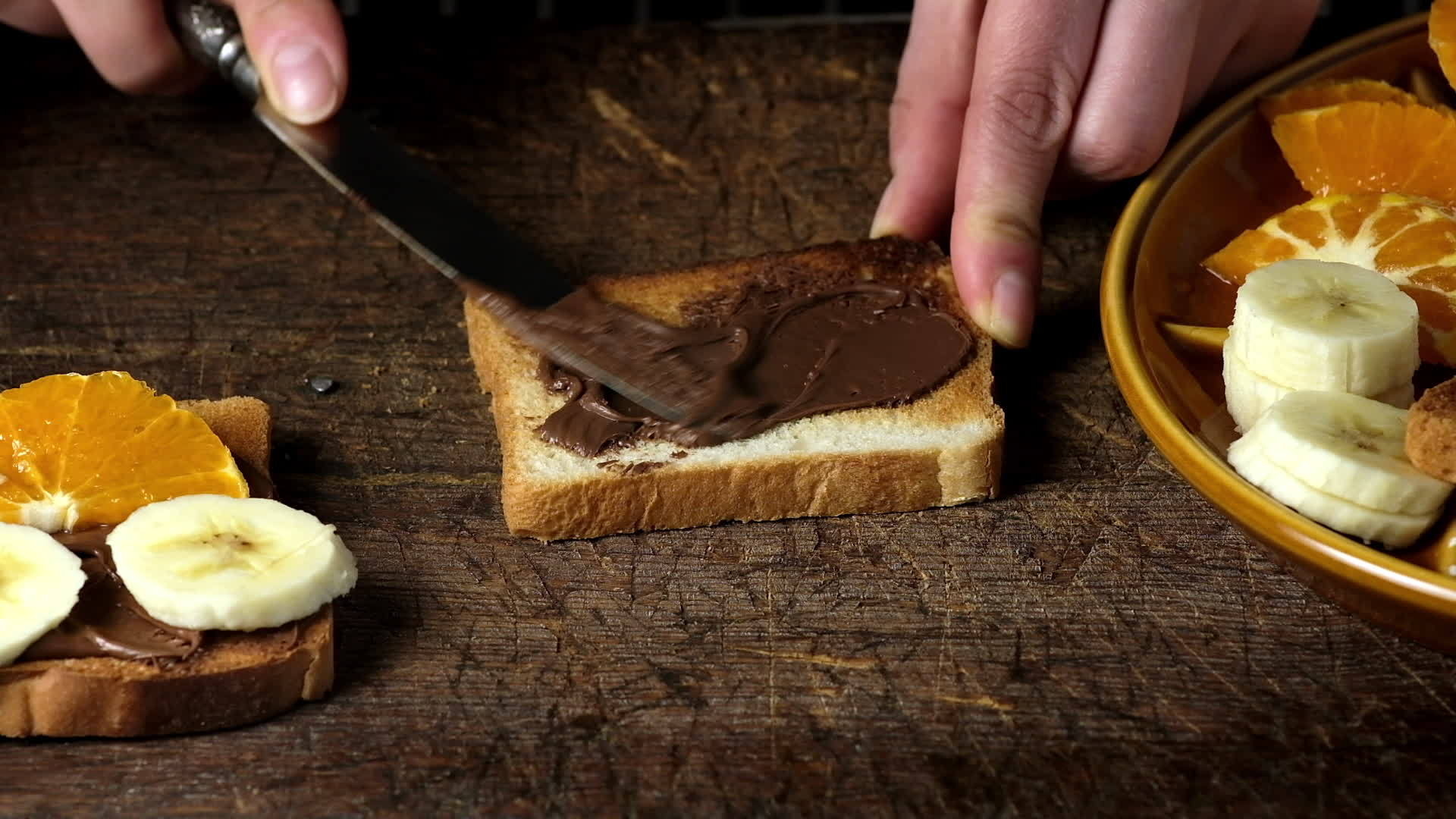 一个女人的手用铁刀在一个方形烤面包上涂上巧克力酱然后在那里视频的预览图