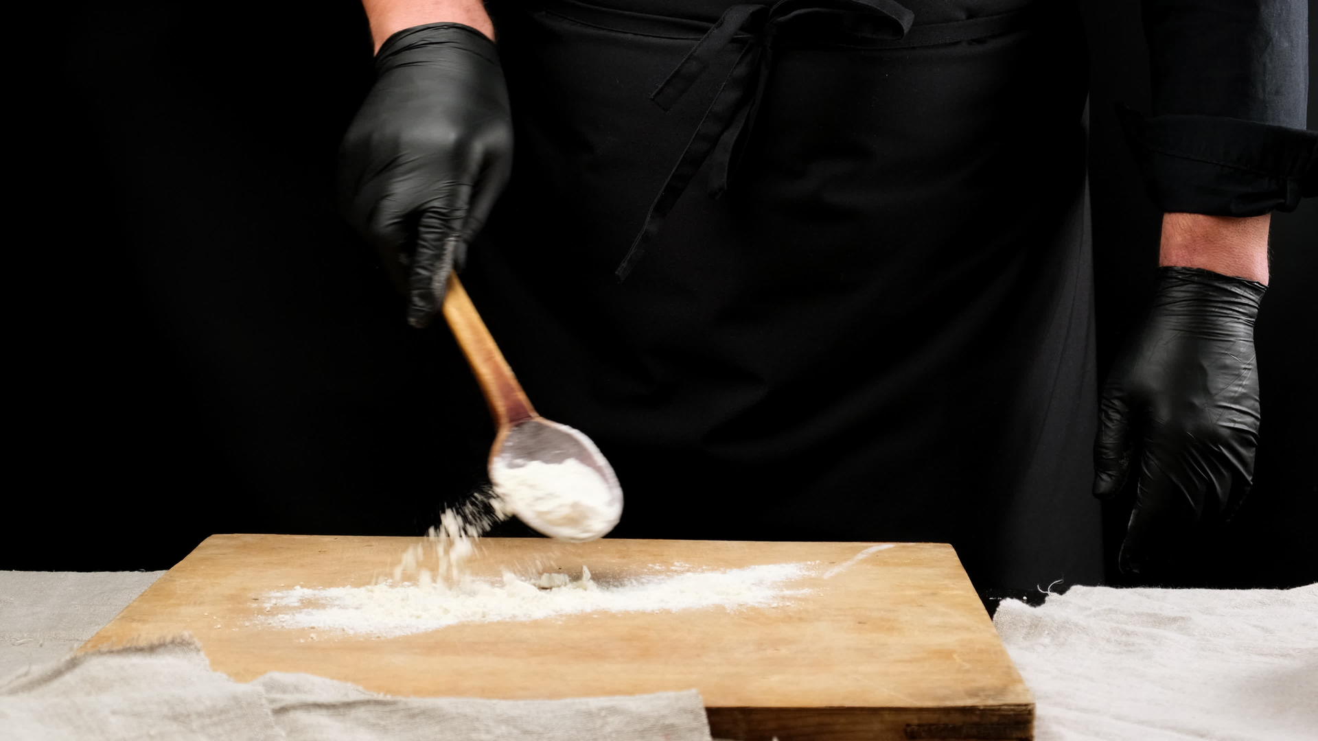 厨师手套穿着黑色制服和黑色乳胶配有一勺白面粉木勺视频的预览图