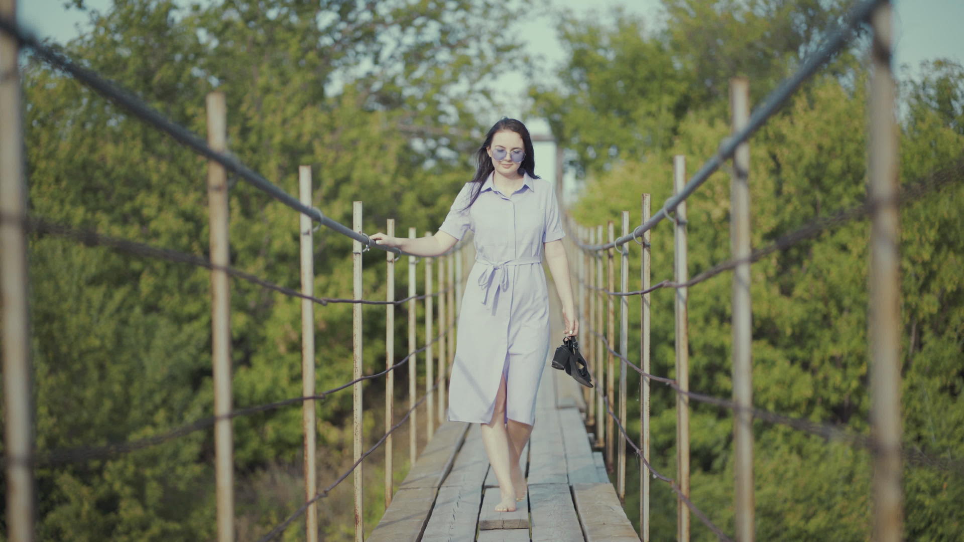 一个穿着漂亮裙子的女人走在树林的桥上女孩手里拿着一个女孩视频的预览图