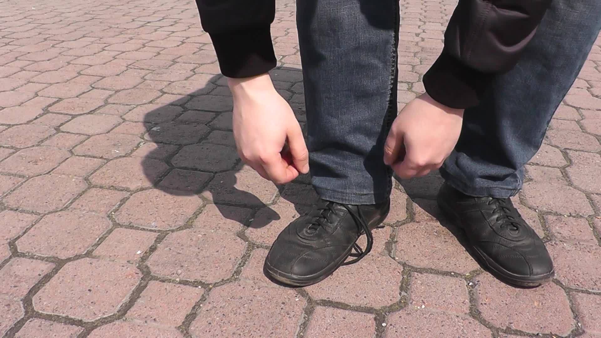 夏天在公园散步的男人把鞋带系在鞋子上视频的预览图