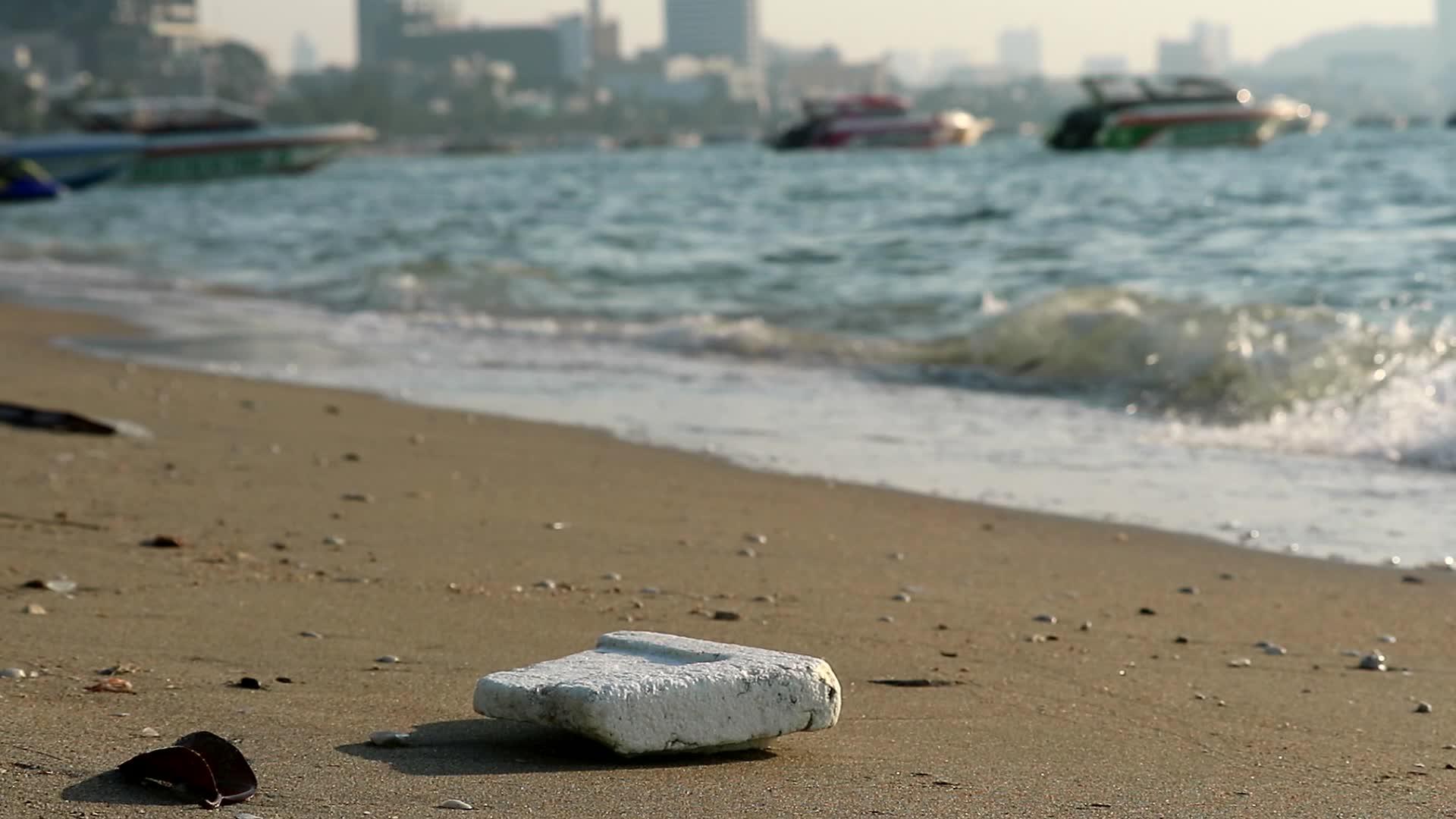 海滩上的泡沫塑料橡胶和废物留在海滩上海浪把它们吹进海里视频的预览图