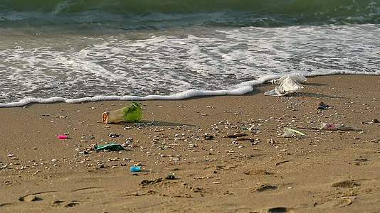 海滩上的塑料杯和废物海浪把它们吹进海里视频的预览图