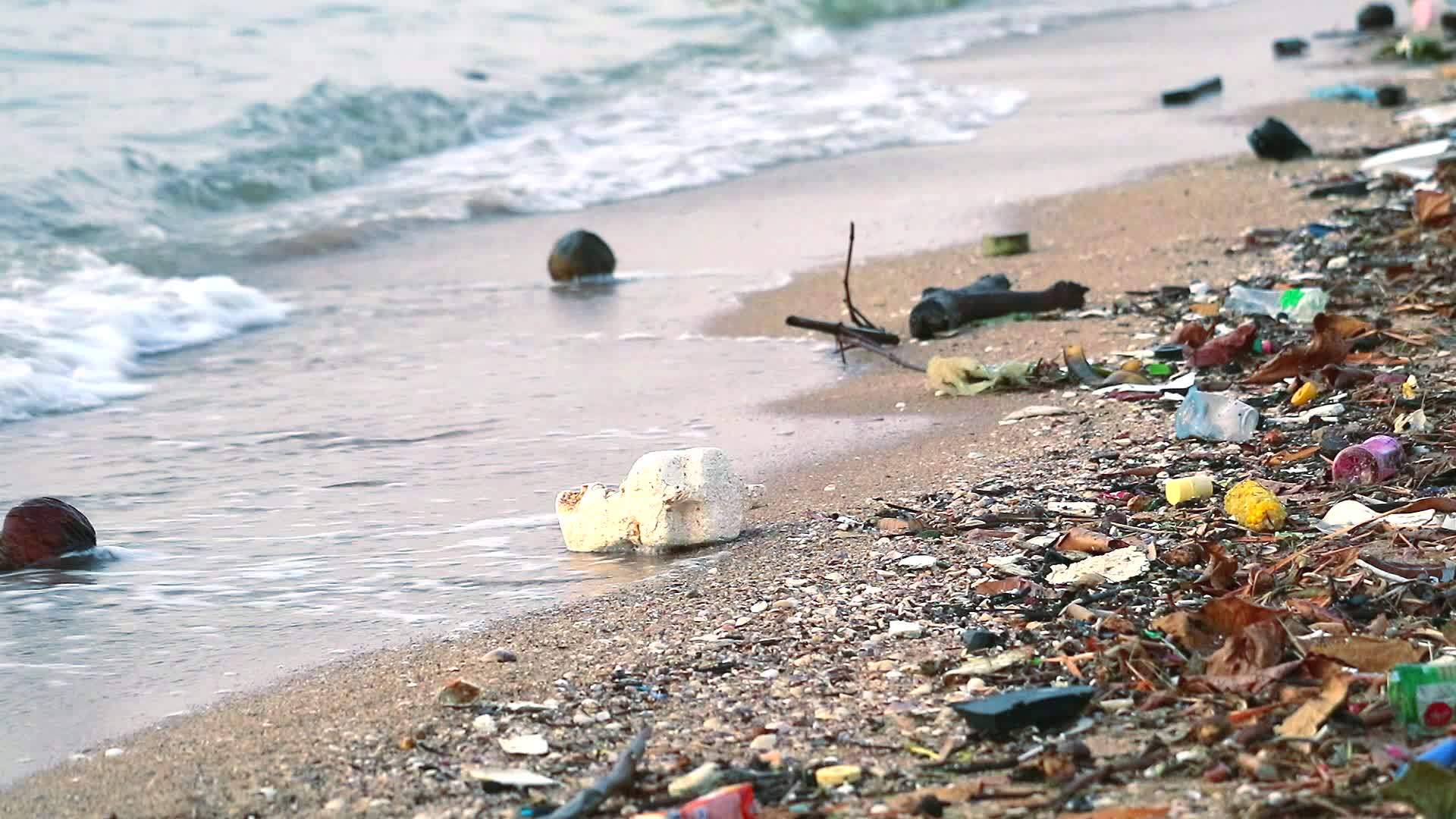 塑料橡胶和废物留在海滩上海面日落海浪把它们吹进海里视频的预览图